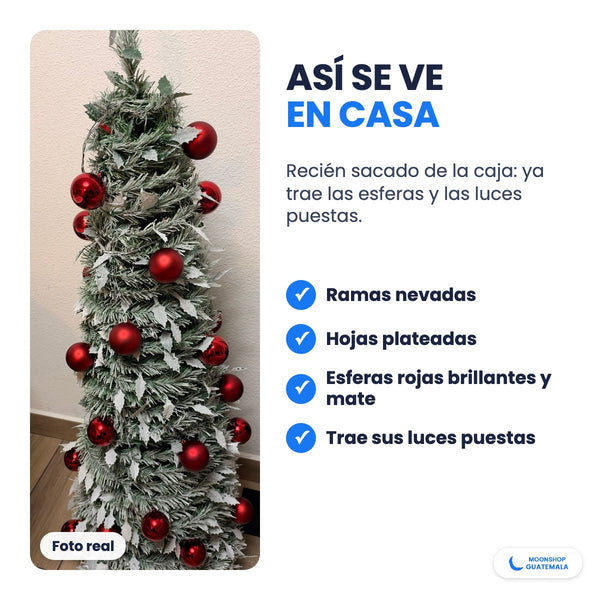 Foto real del árbol de Navidad nevado con esferas rojas y hojas plateadas