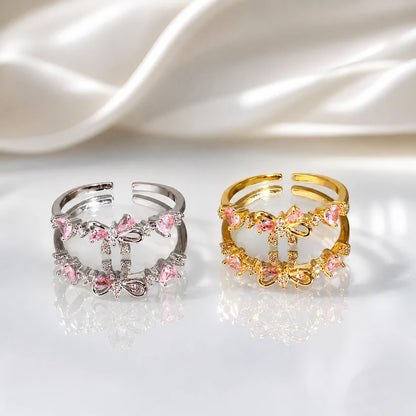 Dos anillos con lazo y cristales rosados, uno plateado y uno dorado