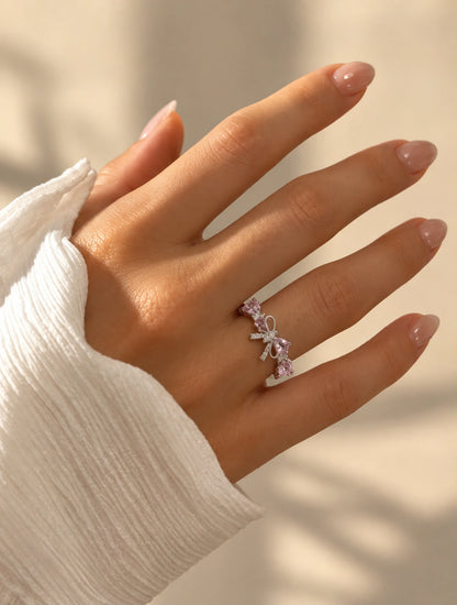 Mano con un anillo de lazo y cristales rosados