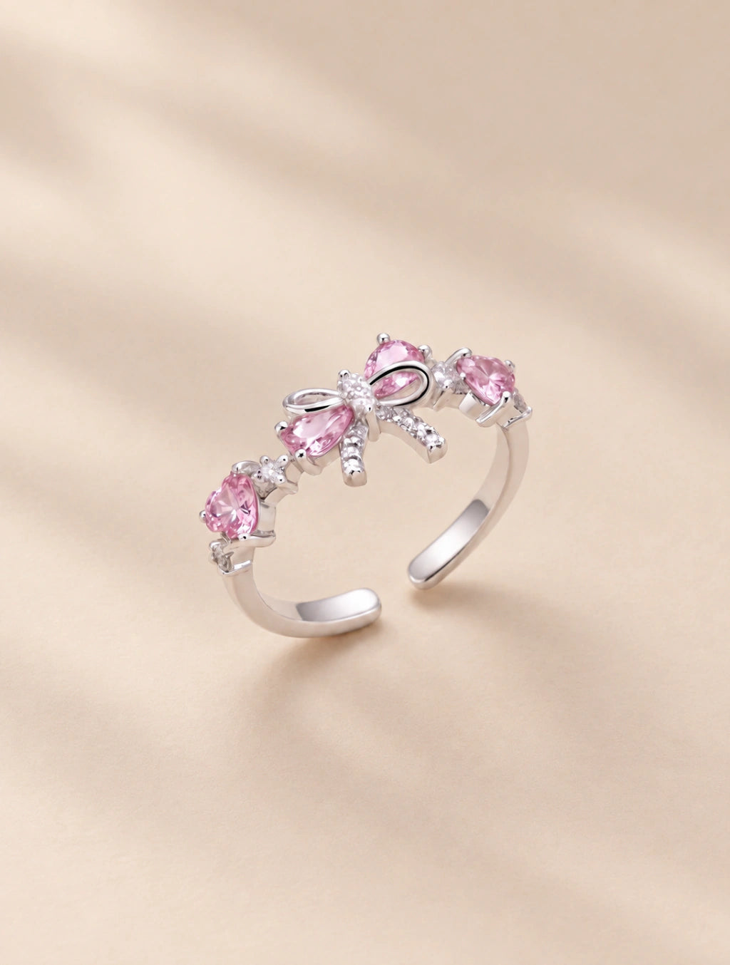 Anillo plateado con lazo y cristales rosados de banda abierta